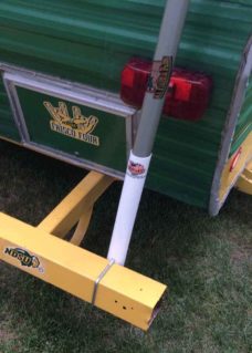 White flagpole bumper mount on a travel trailers back bumper to hold a flagpole. The bumper is yellow in color.